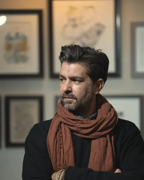 Patrick Scott Armstrong, presenter of Psionics: The Minds That Summon UFOs, photographed against a gallery wall, arms crossed